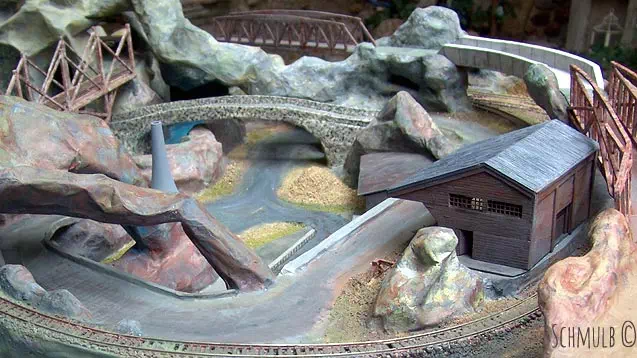 Sculpture d'un paysage en papier mache, avec rocher, pont et rivière.